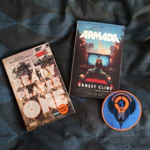 My paperback copies of "Ready Player One" and "Armada," alongside an "Earth Defense Alliance" patch.